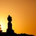 "silhouette of buddha statue and zen-stone pyramid in front of a real sunrise with strong backlighting and beautiful reflections on the stones to underline the spiritual concept,copyspace"